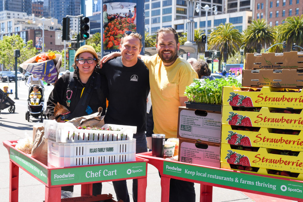 Group photo of three chefs with carts filled with produce at the Ferry Plaza Farmers Market